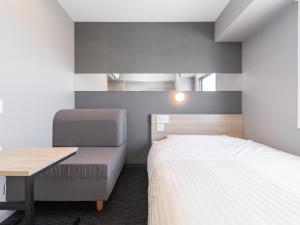a bedroom with a bed and a desk and a bed and a chair at Super Hotel Nagoya Shinkansenguchi in Nagoya
