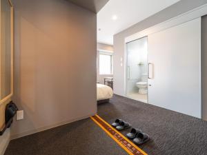 a room with a bed and a pair of shoes at Super Hotel Nagoya Shinkansenguchi in Nagoya