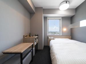 a small room with a bed and a desk and a window at Super Hotel Nagoya Shinkansenguchi in Nagoya
