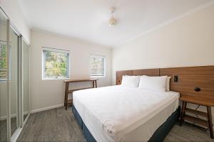 a bedroom with a large bed and two windows at The Sebel Whitsundays in Airlie Beach