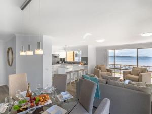 a dining room and living room with a view of the ocean at Pelican Sands 2 fantastic waterfront unit with pool and air conditioning in Soldiers Point