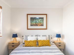 a white bedroom with a bed with two night stands at Pelican Sands 2 fantastic waterfront unit with pool and air conditioning in Soldiers Point