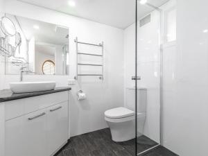 a white bathroom with a toilet and a sink at Pelican Sands 2 fantastic waterfront unit with pool and air conditioning in Soldiers Point +17 photos