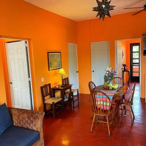 a dining room with orange walls and a table and chairs at Casa Monarca in Chacala