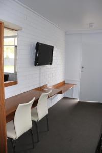 Habitación con escritorio con sillas y TV en la pared. en Edenhope Motor Inn, en Edenhope