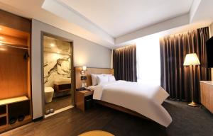 a hotel room with a white bed and a bathroom at Gwangju HOUND Hotel in Gwangju
