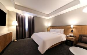 a hotel room with a large white bed and a chair at Gwangju HOUND Hotel in Gwangju