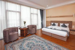 a bedroom with a bed and two chairs and a table at Park Hotel al Bustan in Shymkent