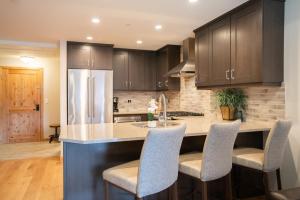 a kitchen with wooden cabinets and a kitchen island with chairs at Spring Creek Serene Luxury at White Spruce Lodge in Canmore