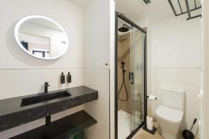 een badkamer met een wastafel, een spiegel en een toilet bij Santa Catalina Suites Gijón in Gijón