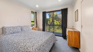 a bedroom with a bed and a large window at Kapiti Views - Waikanae Beach Holiday Home in Waikanae