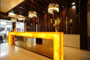 a yellow bench in a lobby with chandeliers at Orange Tree Hotels in Nagpur
