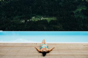 eine Person, die auf einem Deck liegt und auf das Wasser schaut in der Unterkunft Boutique Apartment Sonnenhang - incl Infinity Pool in Fliess