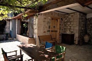 eine Terrasse mit einem Holztisch und Stühlen sowie einem Tisch und einem Tisch in der Unterkunft Small Stone Maisonette 1 in Lílaia