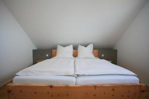 Una cama con sábanas blancas y almohadas. en See-Flair, en Immenstaad am Bodensee