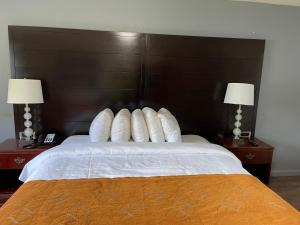 a bedroom with a bed with white pillows and two lamps at Bedford Motel in Bedford