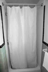 La salle de bains est pourvue d'une douche avec un rideau de douche blanc. dans l'établissement Bedford Motel, à Bedford