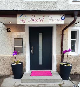 een zwarte voordeur met een roze kleed voor bij my Hostel Füssen in Füssen