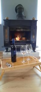 two wine glasses and a bottle on a table in front of a fireplace at House Anita in Grabovac