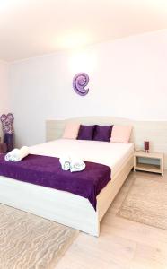 a bedroom with a large bed with purple sheets at Vila Adriana in Eforie Nord
