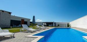 a swimming pool with lounge chairs next to a building at Luxury Villa in Mostar in Mostar