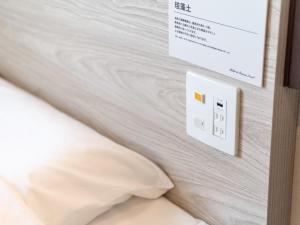 a bedroom with a white bed with a light switch at Super Hotel Nagoya Shinkansenguchi in Nagoya