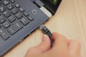 a person is holding a usb cord plugged into a laptop computer at Super Hotel Nagoya Shinkansenguchi in Nagoya