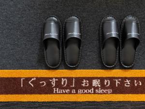 a pair of black shoes on top of a yellow stripe at Super Hotel Nagoya Shinkansenguchi in Nagoya