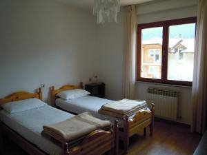 due letti singoli in una stanza con finestra di Appartamenti Rosenberger a Molveno