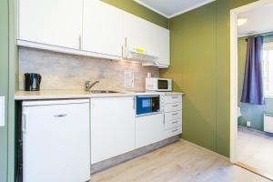 una cocina con armarios blancos y paredes verdes en Easy Home Apartments en Hammerfest