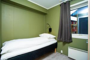 a bed in a green room with a window at Easy Home Apartments in Hammerfest