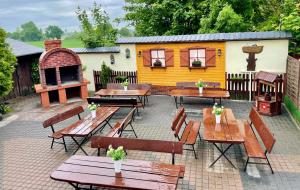 a patio with wooden tables and chairs and a building at Przystań Biskupińska in Biskupin
