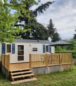 a tiny house with a deck and an umbrella at Mobil-home Beau Rivage in Gunsbach