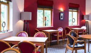 a restaurant with red walls and tables and chairs at Holiday Inn Express Inverness, an IHG Hotel in Inverness