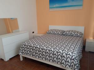 a bedroom with a bed with a black and white comforter at Appartamenti Le Dune in Foce Varano