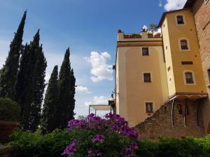 un edificio con fiori viola di fronte di Residence Le Santucce a Castiglion Fiorentino