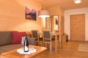 Sala de estar con sofá y mesa con botella de vino en Villa Alpin, en Holzgau