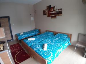 a bedroom with two beds with blue sheets and a chair at Goka apartments in Gevgelija