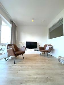ein Wohnzimmer mit 2 Stühlen und einem Flachbild-TV in der Unterkunft Residenz Am Hang in Scharbeutz