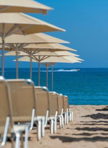 a row of beach chairs sitting on top of a beach at Ilios Beach Hotel Apartments ADULTS ONLY in Rethymno