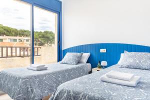 two beds in a room with a large window at Molí del Mar in L'Escala