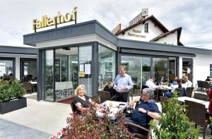grupa ludzi siedzących przed restauracją w obiekcie Hotel Restaurant Fallerhof w mieście Bad Krozingen