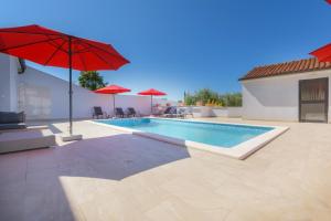 a swimming pool with a red umbrella and a pool at Relaxing villa Mala vala in Fažana