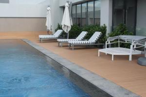 una piscina con sedie a sdraio e tavolo e una piscina di Furnished, 1-bedroom, luxury apartment in Menlyn Maine a Pretoria