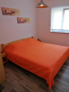 sypialnia z łóżkiem z pomarańczowym kocem w obiekcie Apartman Rafael w Medulinie