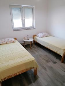 Pokój z 2 łóżkami i stołem oraz 2 oknami w obiekcie Apartman Rafael w Medulinie