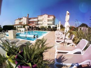 une piscine avec des chaises longues blanches et un bâtiment dans l'établissement Villa Badi, à Umag