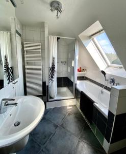 ein Badezimmer mit einem Waschbecken, einer Badewanne und einer Dusche in der Unterkunft Ferienhaus mit 5* Luxus im Schwarzwald in Gemeinde Aichhalden