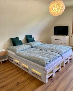 Schlafzimmer mit einem Bett mit einem TV und einem Kronleuchter in der Unterkunft Ferienhaus mit 5* Luxus im Schwarzwald in Gemeinde Aichhalden