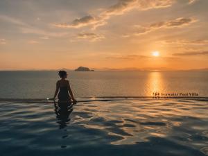 a woman sitting in a infinity pool watching the sunset at Santhiya Koh Yao Yai Resort & Spa - Compulsory Join Santhiya Speedboat from-to Ao Po Grand Marina at Phuket in Ko Yao Yai